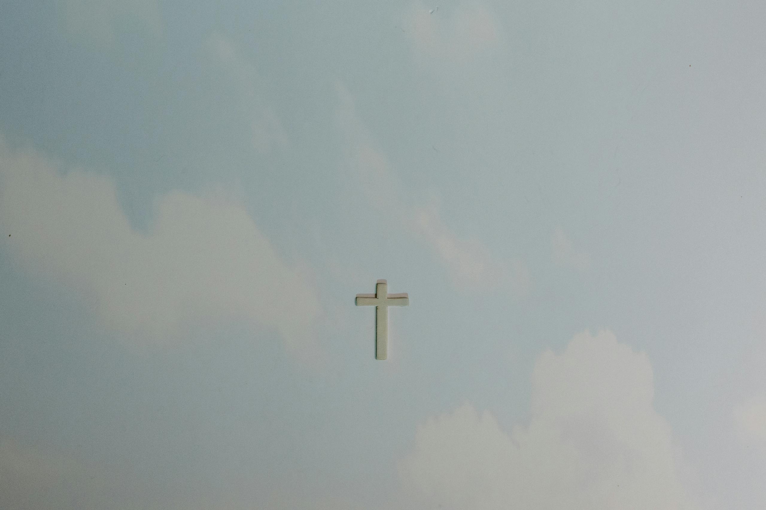 A solitary cross set against a softly clouded sky, symbolizing peace and spirituality.